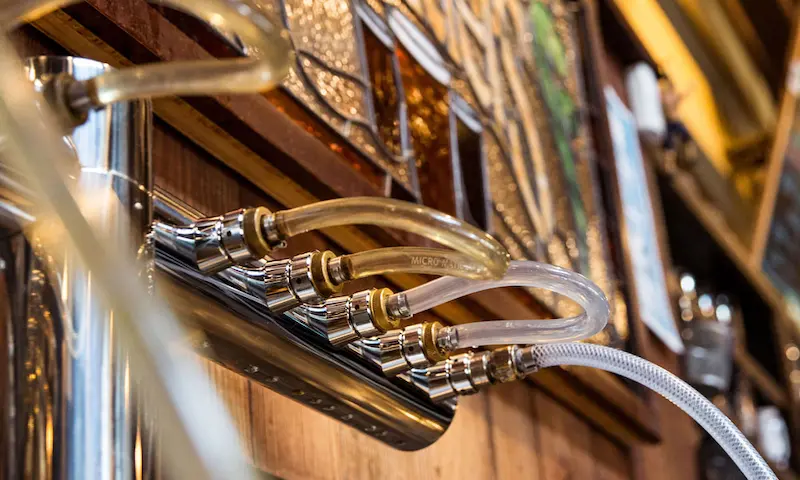 Clear jumper lines connecting the faucets on a wall-mounted beer tap during a draft line cleaning in Philadelphia
